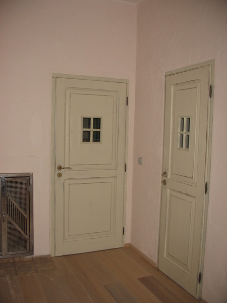 Patinované dveře v barvě slonové kosti, s porcelánovou klikou.       	